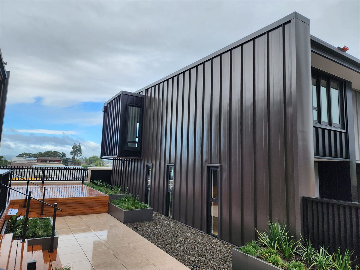 Dark vertical Espan cladding on a Hawkins townhouse courtyard building completed by ADCO Roofing.