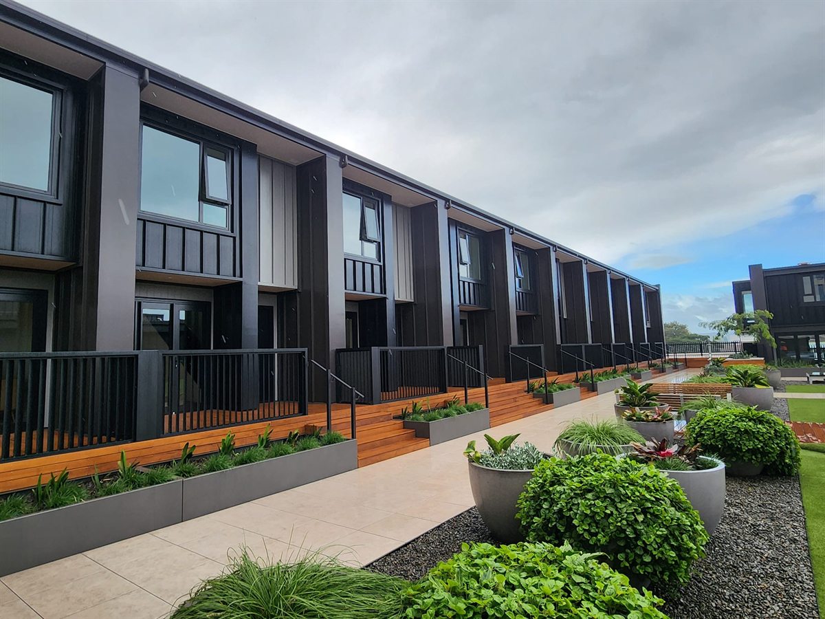 Hawkins Tauranga CBD townhouse block with Coloursteel Espan cladding, timber decking, and landscaped planters.