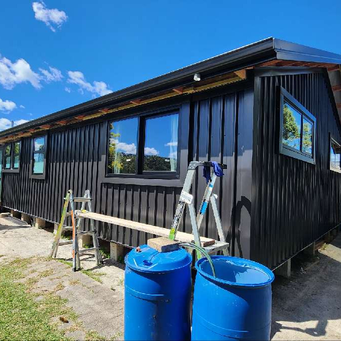 The same home after ADCO Roofing's reclad in dark Flaxpod 5 Rib cladding with a new Coloursteel roof, fascia and spouting.