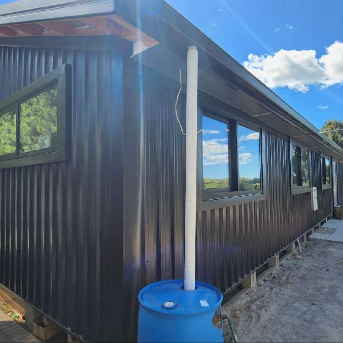 Completed dark Flaxpod 5 Rib reclad with new Coloursteel roof, fascia, spouting and downpipe by ADCO Roofing.