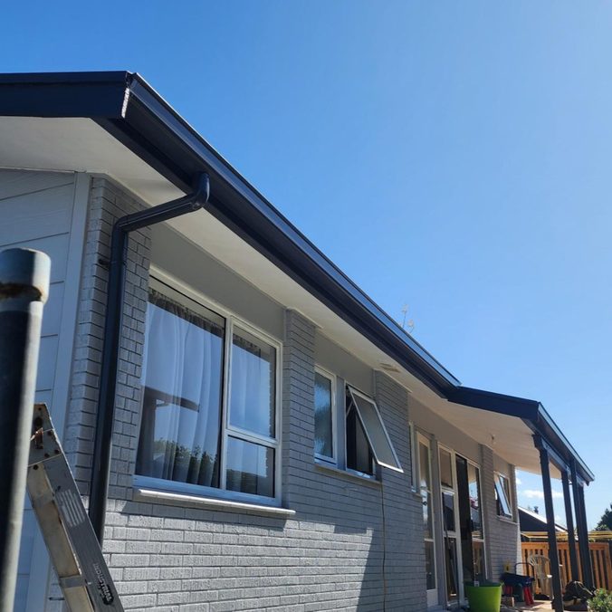 Completed dark 5 Rib longrun roof conversion with matching fascia and spouting on a brick home by ADCO Roofing.